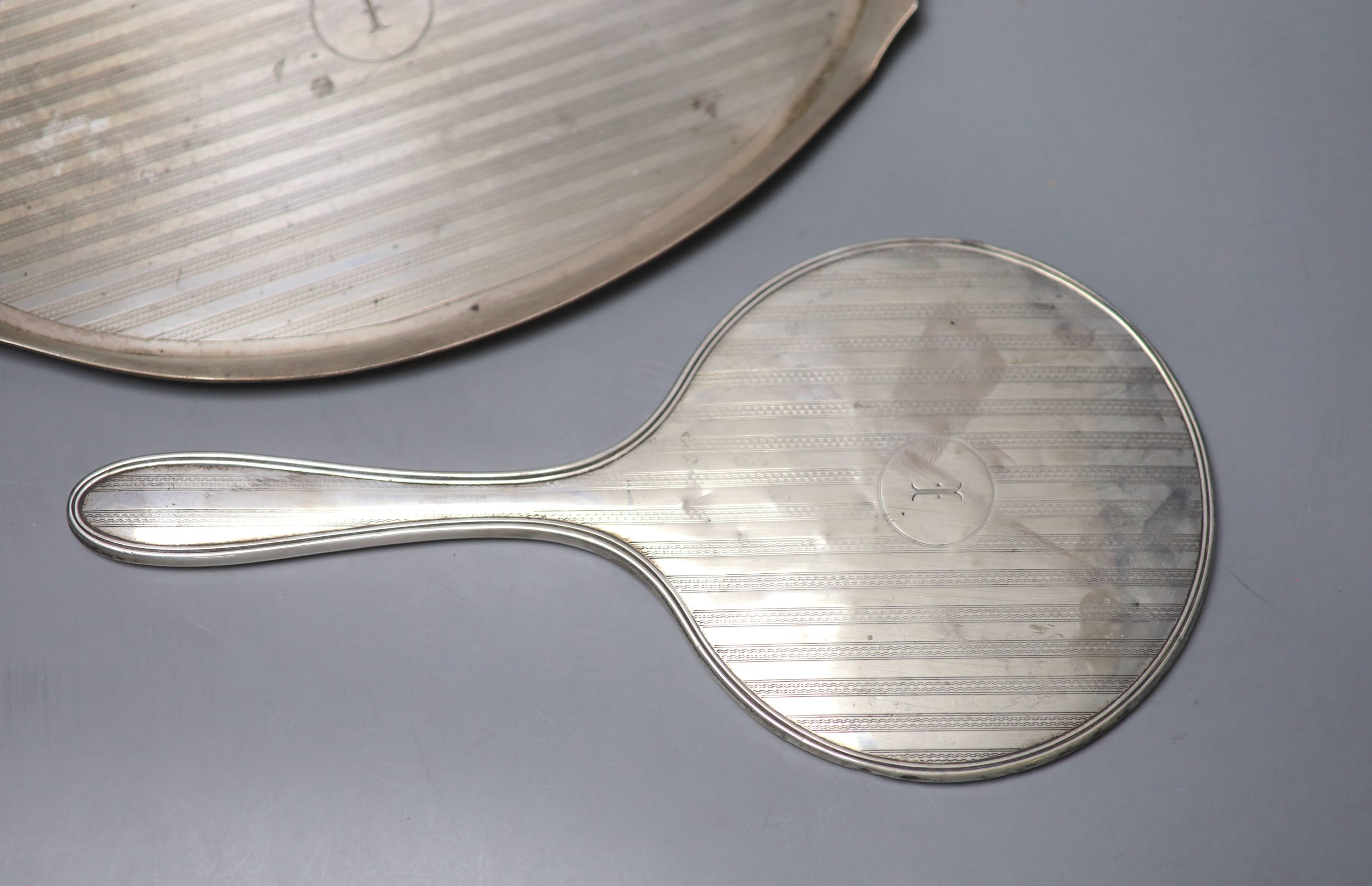 A George V silver oval dressing table tray, Birmingham, 1924, 31.3cm and a matching silver mounted hand mirror,